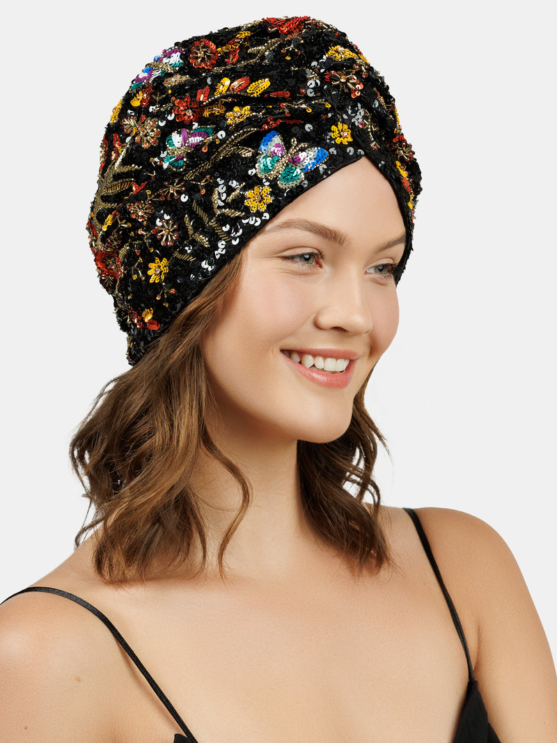White female model wearing hand made sequin-embellished black turban. Tridimensional butterfly and floral pattern designed by Maryjane Claverol