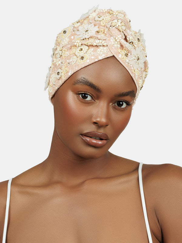 Black female model wearing hand made sequin-embellished peach color turban with a tridimensional tonal flower pattern design by Maryjane Claverol