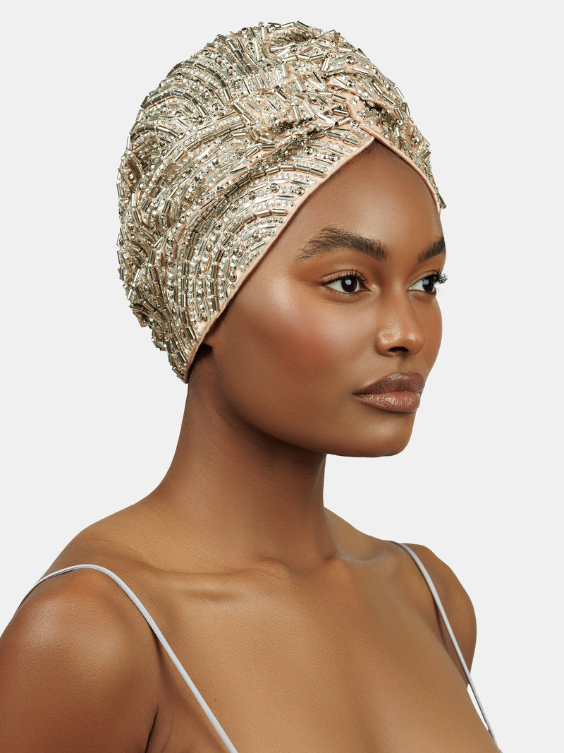 3/4 view of female model wearing handmade silver sequin and palette embroidered blush colored turban designed by Maryjane Claverol