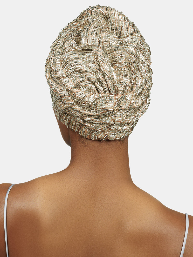 Back view of female model wearing handmade silver sequin and palette embroidered blush colored turban designed by Maryjane Claverol
